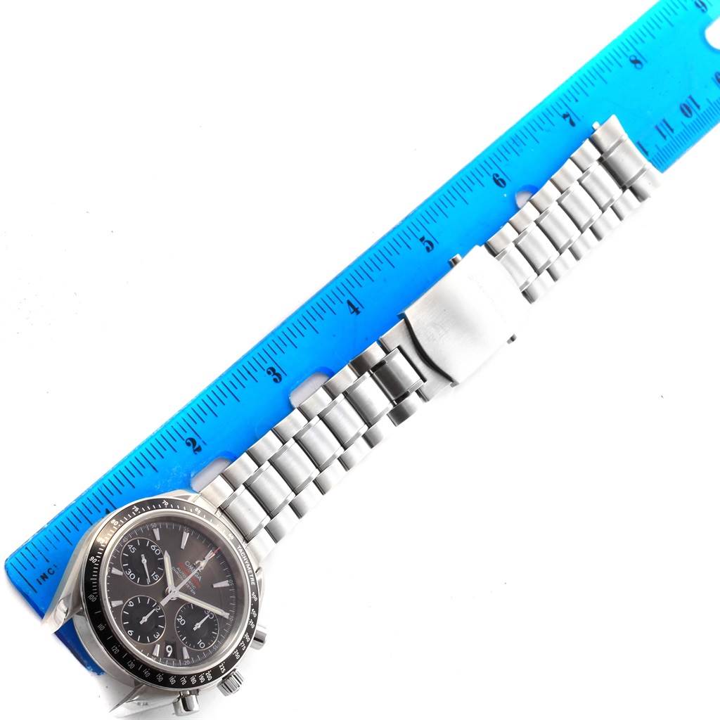 The Omega Speedmaster 323.30.40.40.06.001 Men
s Stainless Steel Grey Dial 323.30.40.40.06.001 Men
s Stainless Steel Grey Dial watch is shown from above, displaying its face, bezel, and metal bracelet next to a blue ruler.