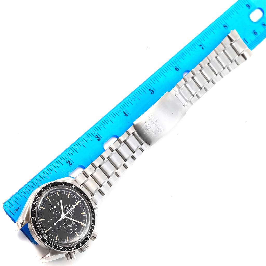 The image shows an Omega Speedmaster 3570.50.00 Men
s Stainless Steel Black Dial 3570.50.00 Men
s Stainless Steel Black Dial watch laid flat with a blue ruler measuring its bracelet length.