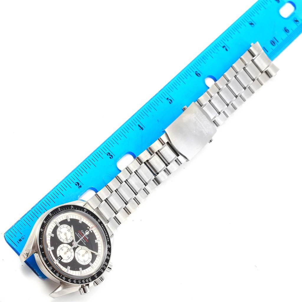 The image shows an Omega Speedmaster 3507.51.00 Men
s Stainless Steel Black Dial 3507.51.00 Men
s Stainless Steel Black Dial watch laying flat with its face and metal bracelet, positioned next to a blue ruler.