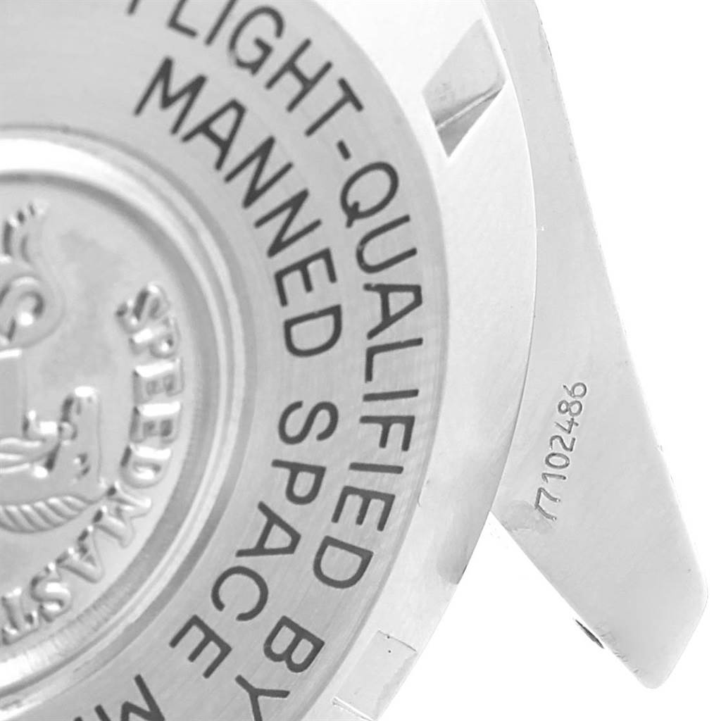 The image shows the back of an Omega Speedmaster Men
s Stainless Steel Black Dial Men
s Stainless Steel Black Dial watch, focusing on the engraved text and part of the watch
s lug with the serial number.