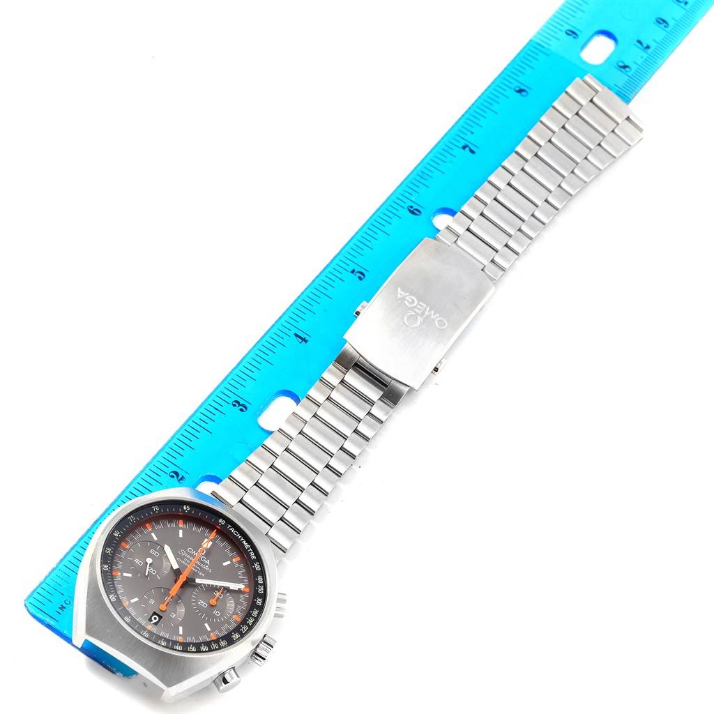 The Omega Speedmaster 327.10.43.50.06.001 Men
s Stainless Steel Grey Dial 327.10.43.50.06.001 Men
s Stainless Steel Grey Dial watch is displayed flat against a ruler, showcasing its face, stainless steel band, and clasp.