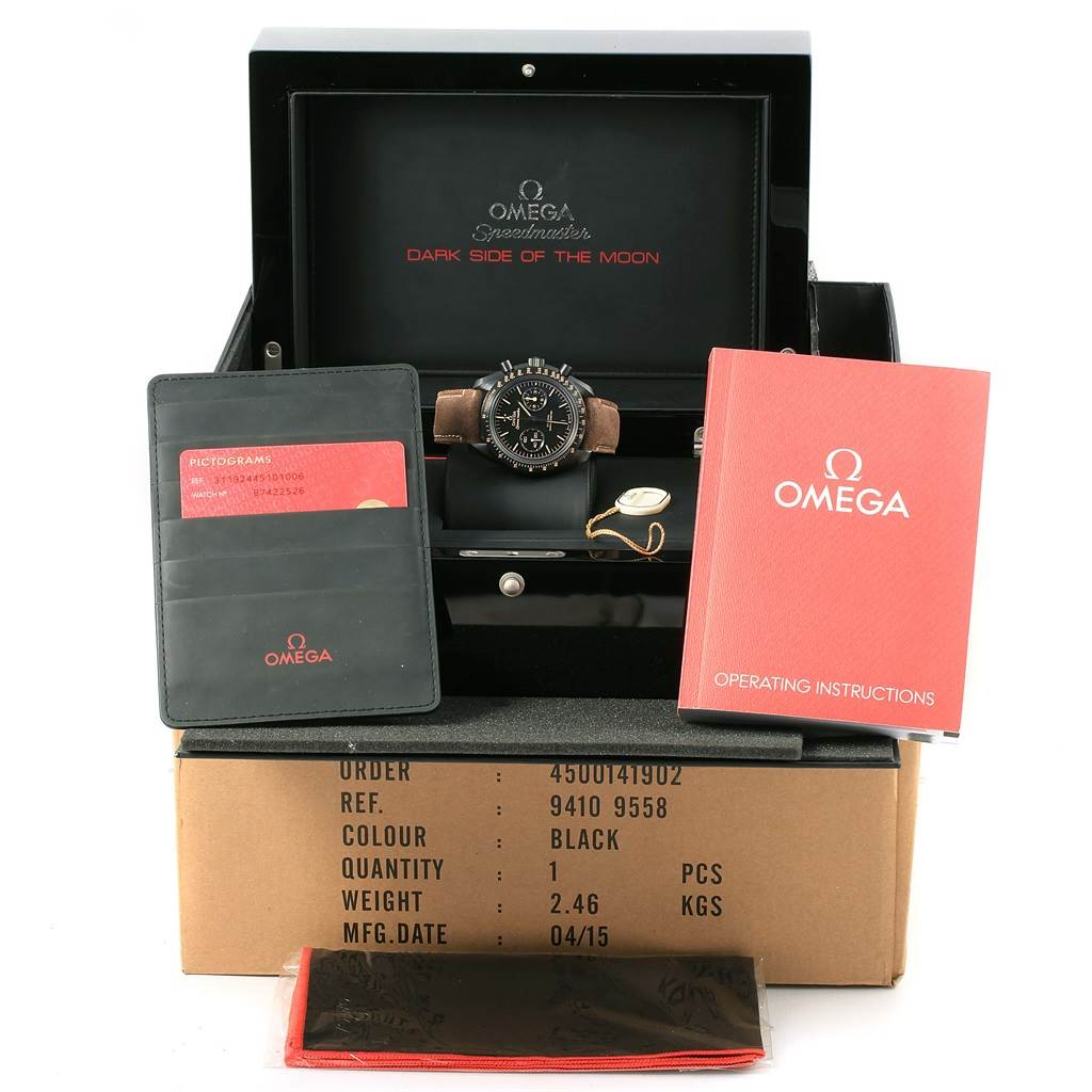 The image shows an Omega Speedmaster 311.92.44.51.01.006 Men
s Stainless Steel Black Dial 311.92.44.51.01.006 Men
s Stainless Steel Black Dial watch at an eye-level angle, with its box, instruction manual, warranty card, and additional accessories.