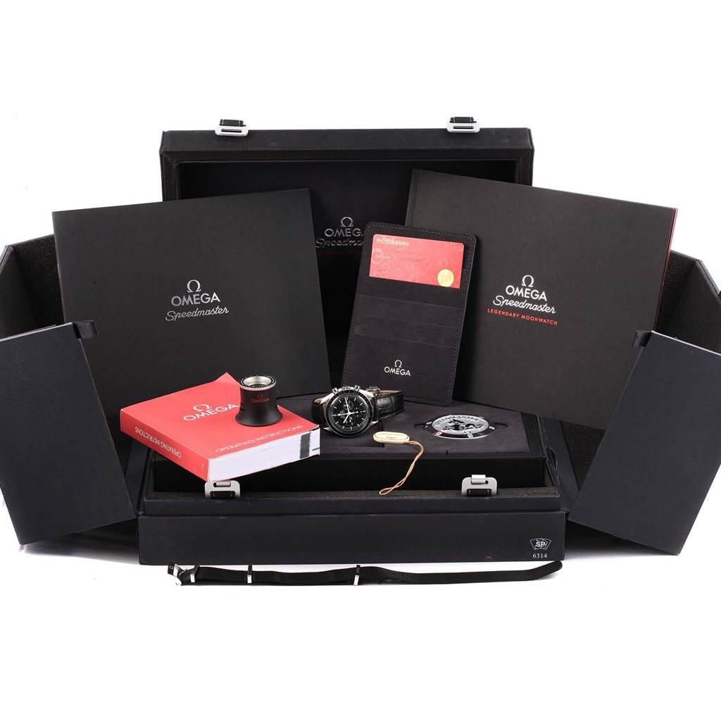 The image shows an Omega Speedmaster 311.30.42.30.01.005 Men
s Stainless Steel Black Dial 311.30.42.30.01.005 Men
s Stainless Steel Black Dial watch and accessories in its packaging, including manuals, a tool, and a warranty card.
