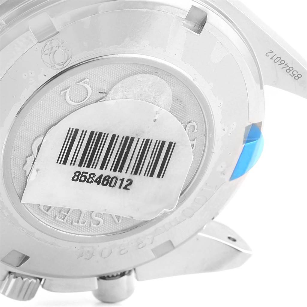 The image shows the back case of an Omega Speedmaster 323.30.40.40.06.001 Men's Stainless Steel Grey Dial 323.30.40.40.06.001 Men's Stainless Steel Grey Dial watch with a barcode sticker and some serial numbers visible.