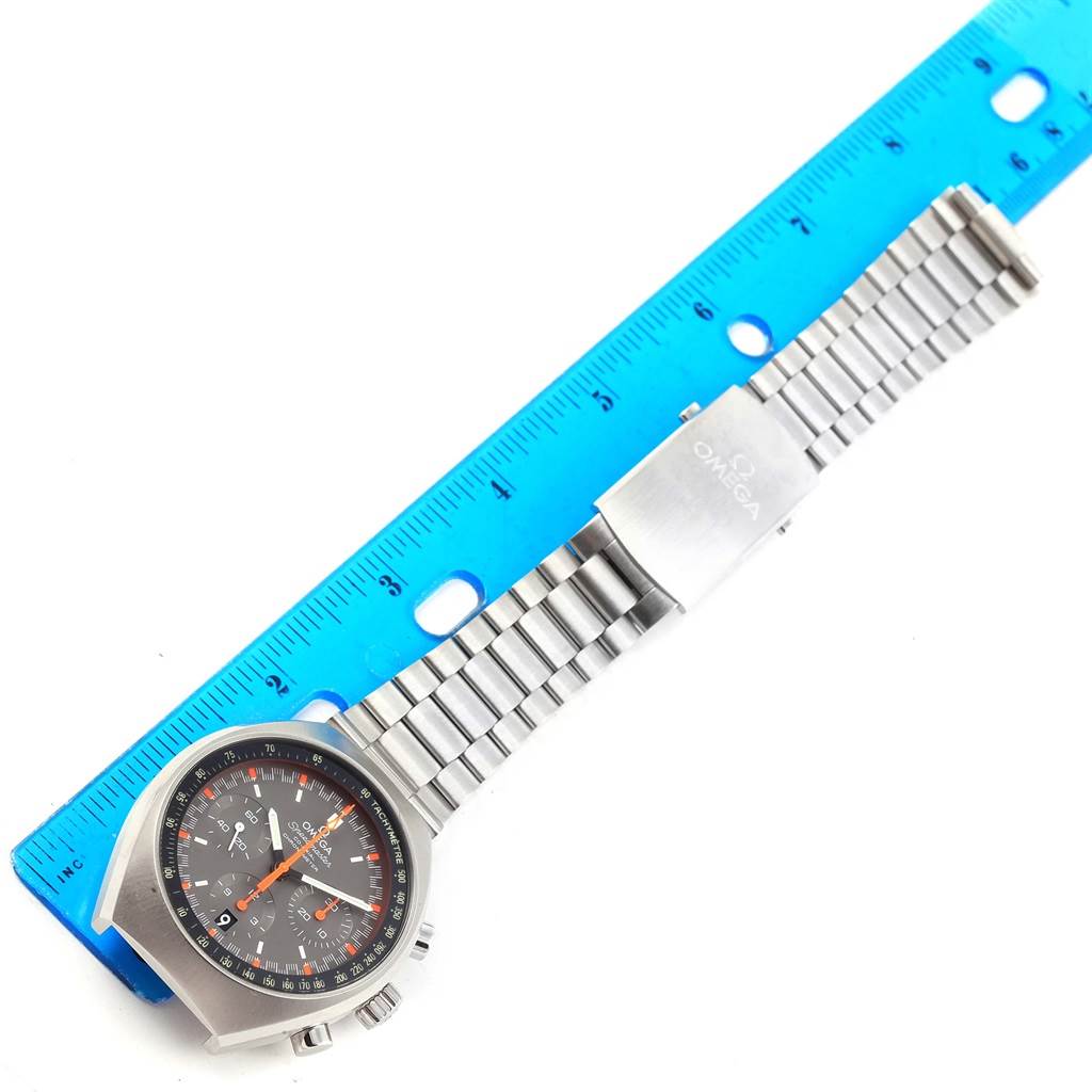 The Omega Speedmaster 327.10.43.50.06.001 Men
s Stainless Steel Grey Dial 327.10.43.50.06.001 Men
s Stainless Steel Grey Dial watch is shown at an overhead angle, displaying its face, bracelet, and clasp alongside a blue ruler.