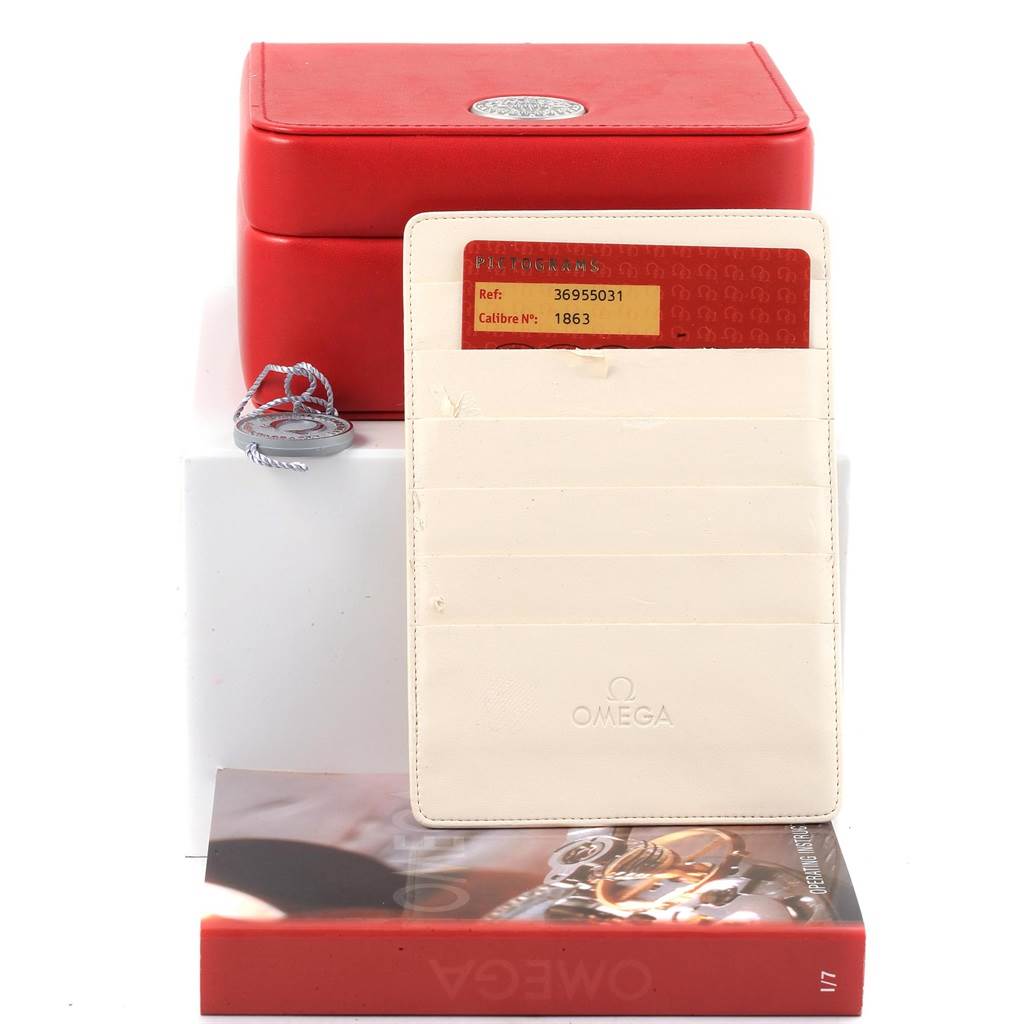 The image shows a red Omega Speedmaster 3695.50.31 Men's Yellow Gold Black Dial 3695.50.31 Men's Yellow Gold Black Dial watch box, a warranty card in a holder, a booklet, and a tag, viewed from the front.