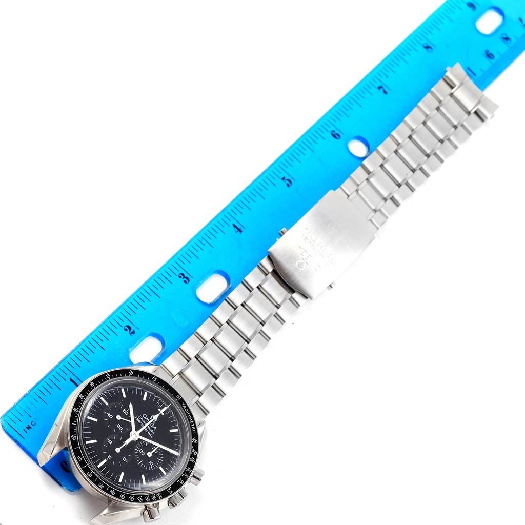 The Omega Speedmaster 3570.50.00 Men
s Stainless Steel Black Dial 3570.50.00 Men
s Stainless Steel Black Dial watch is shown lying flat next to a blue ruler, displaying its face, bezel, case, and metal bracelet.