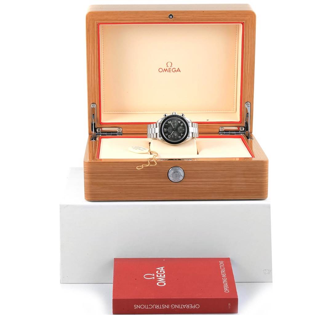 The image shows an Omega Speedmaster 324.30.38.40.06.001 Men
s Stainless Steel Grey Dial 324.30.38.40.06.001 Men
s Stainless Steel Grey Dial watch inside an open wooden box with a user manual placed in front of it.
