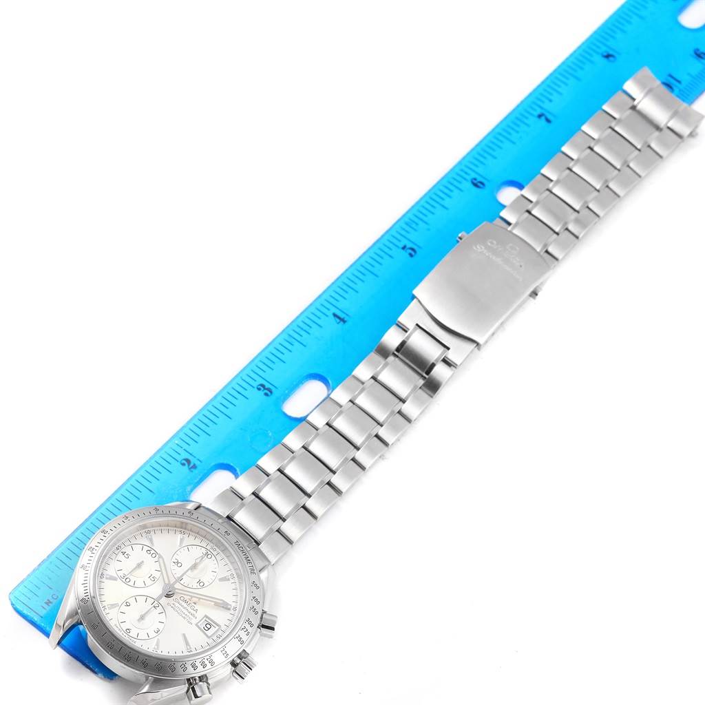 The image shows an Omega Speedmaster 3211.30.00 Men
s Stainless Steel Silver Dial 3211.30.00 Men
s Stainless Steel Silver Dial watch with its stainless steel bracelet laid flat next to a ruler.