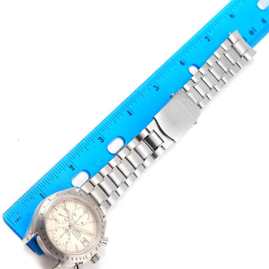 This image shows an Omega Speedmaster 3211.30.00 Men
s Stainless Steel Silver Dial 3211.30.00 Men
s Stainless Steel Silver Dial watch laid flat against a ruler, displaying the watch face and metal bracelet.