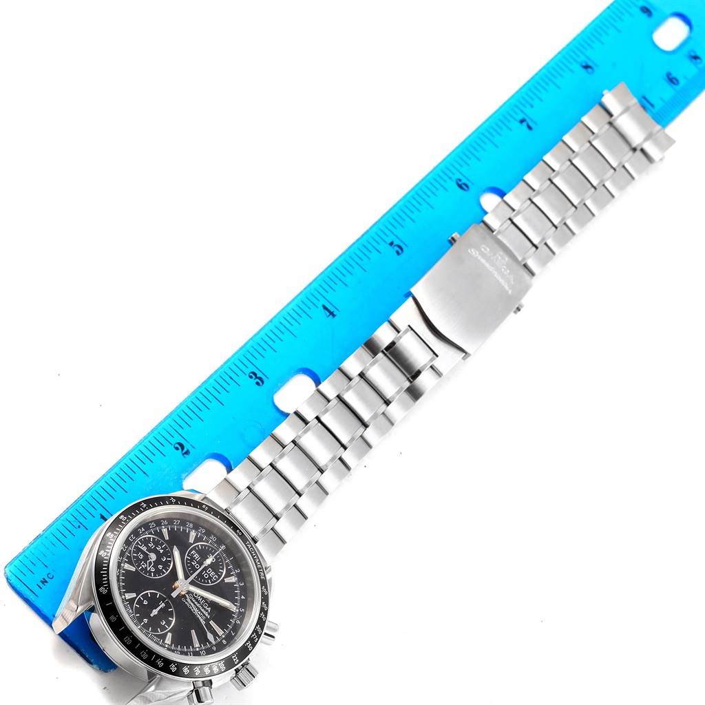 The image shows an Omega Speedmaster 3220.50.00 Men
s Stainless Steel Black Dial 3220.50.00 Men
s Stainless Steel Black Dial watch with a metal bracelet laid next to a blue ruler for measurement.