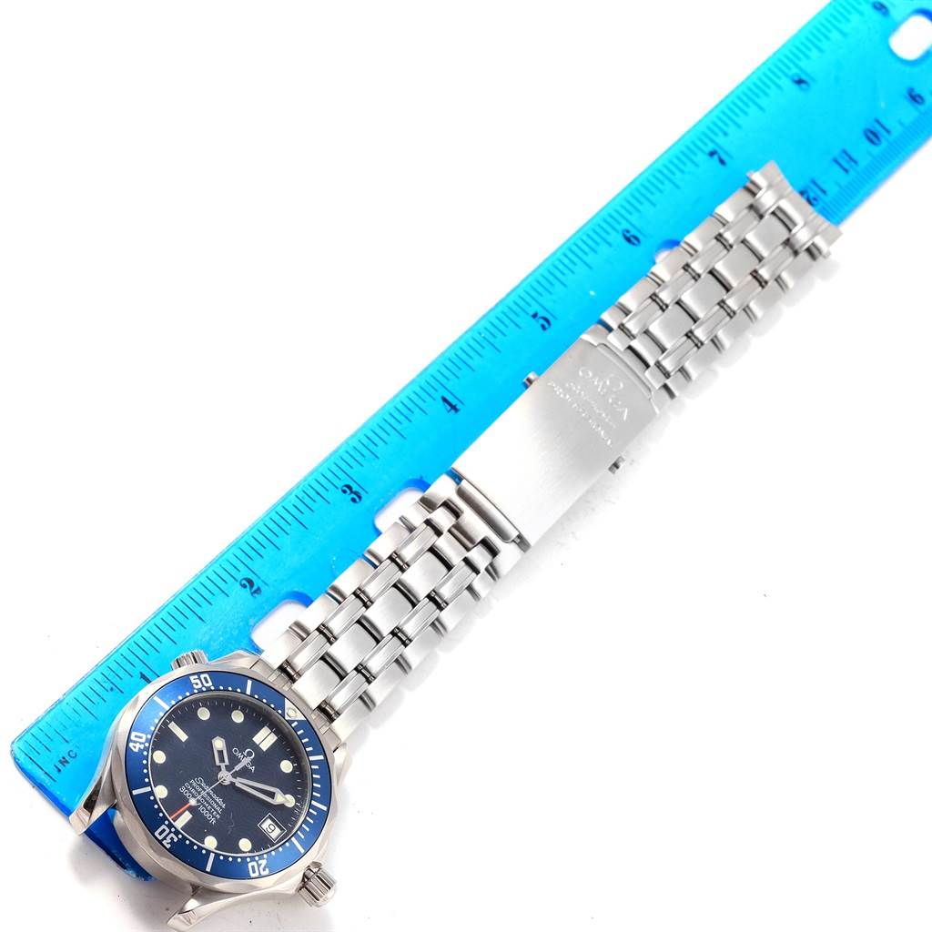 The image shows an Omega Speedmaster 2551.80.00 Men
s Stainless Steel Blue Dial 2551.80.00 Men
s Stainless Steel Blue Dial watch laid next to a ruler, displaying the face and metal bracelet from a top-down angle.