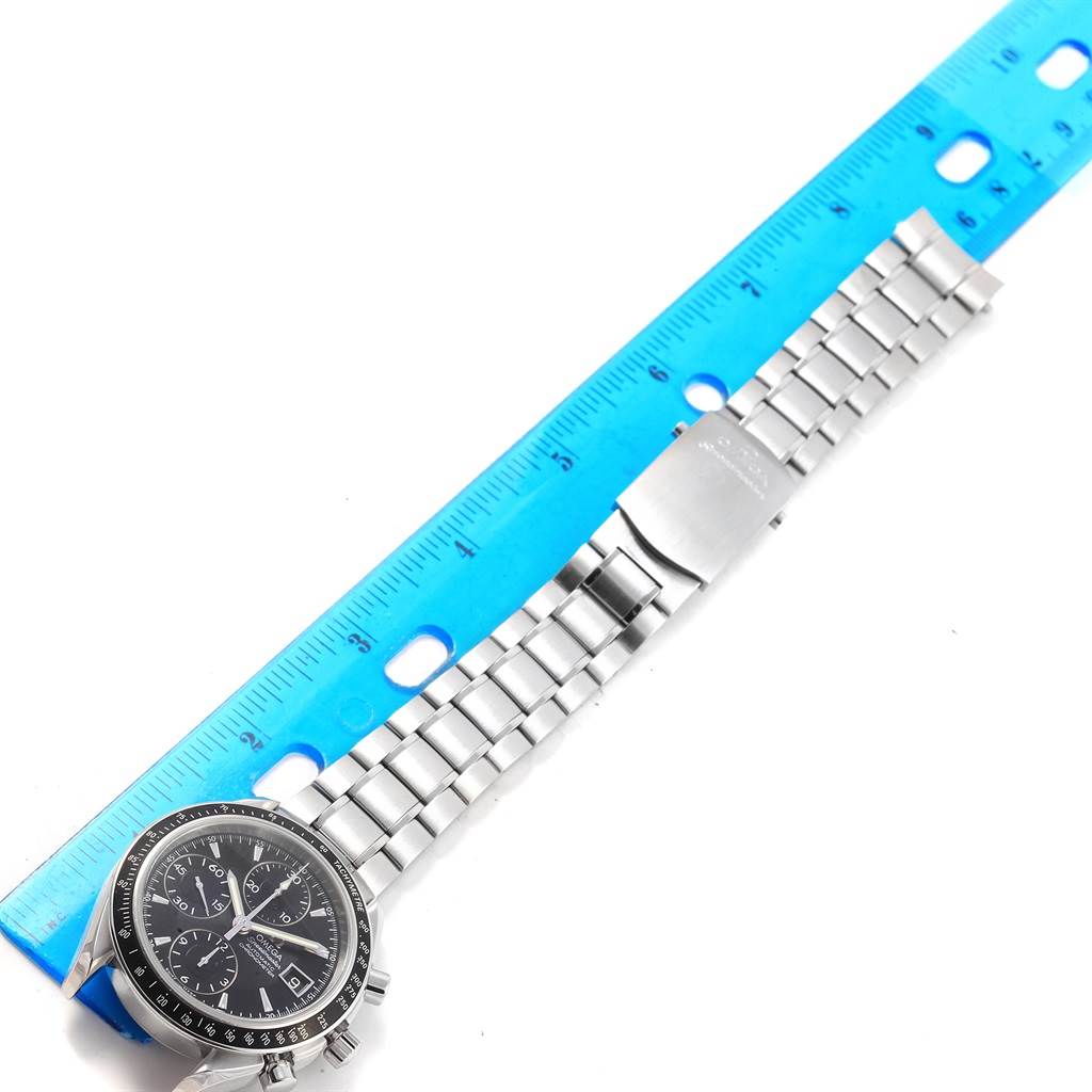 The image shows an Omega Speedmaster 3210.50.00 Men
s Stainless Steel Black Dial 3210.50.00 Men
s Stainless Steel Black Dial watch laid flat with its metal bracelet, next to a blue ruler for scale.