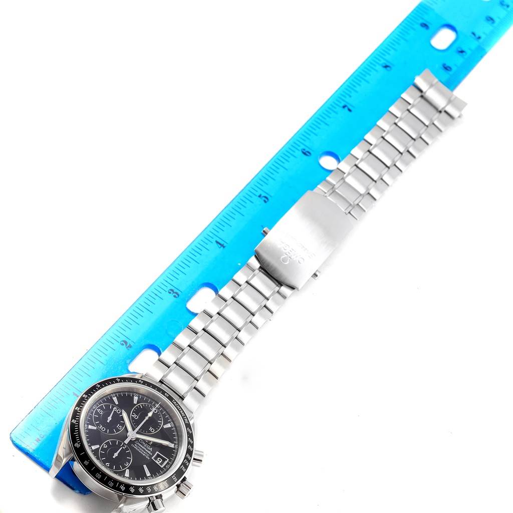 The image shows an Omega Speedmaster 3210.50.00 Men
s Stainless Steel Black Dial 3210.50.00 Men
s Stainless Steel Black Dial watch and its stainless steel bracelet laid flat beside a blue ruler.