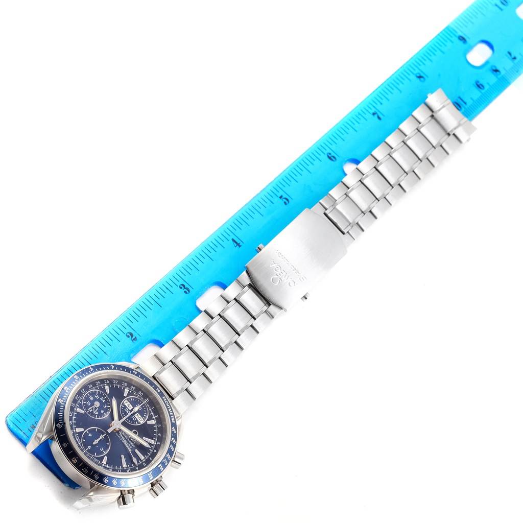 The image shows an Omega Speedmaster 3222.80.00 Men
s Stainless Steel Blue Dial 3222.80.00 Men
s Stainless Steel Blue Dial watch laying flat with a blue ruler for scale, highlighting its face and metal bracelet.