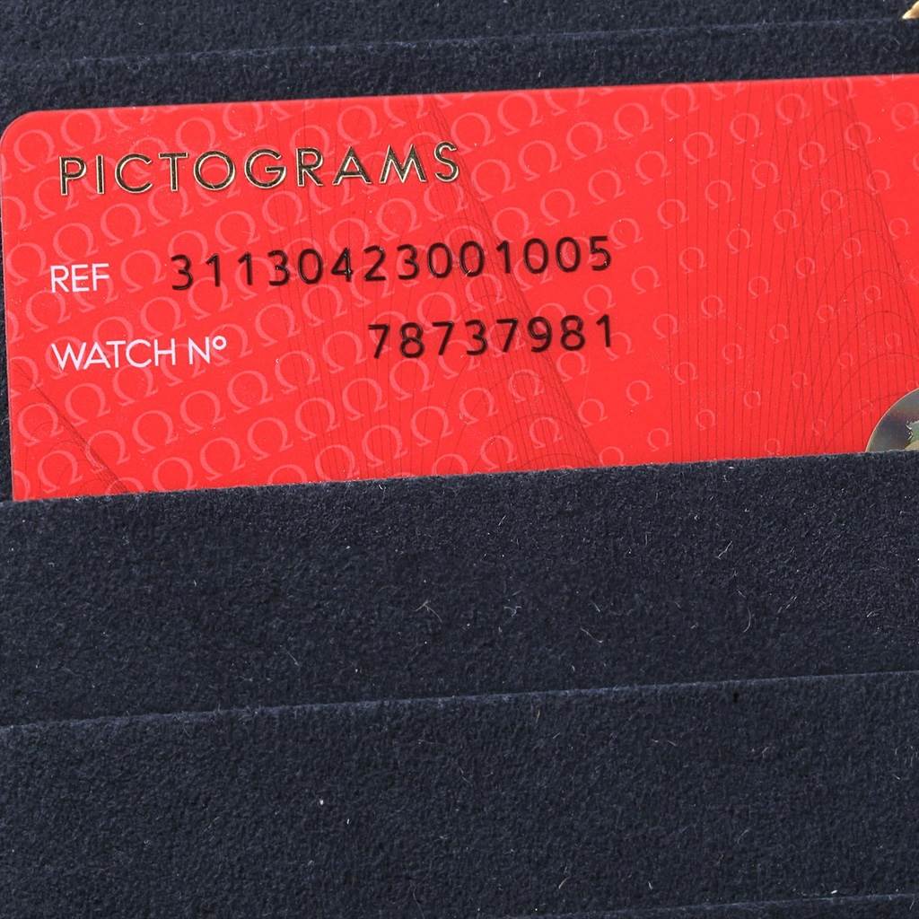 The image shows a red Omega Speedmaster 311.30.42.30.01.005 Men
s Stainless Steel Black Dial 311.30.42.30.01.005 Men
s Stainless Steel Black Dial Pictograms card with reference and watch numbers partially inserted in a dark sleeve.