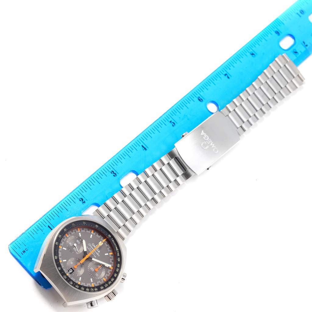 The image shows an Omega Speedmaster 327.10.43.50.06.001 Men
s Stainless Steel Grey Dial 327.10.43.50.06.001 Men
s Stainless Steel Grey Dial watch laid flat with a blue ruler to measure its length.