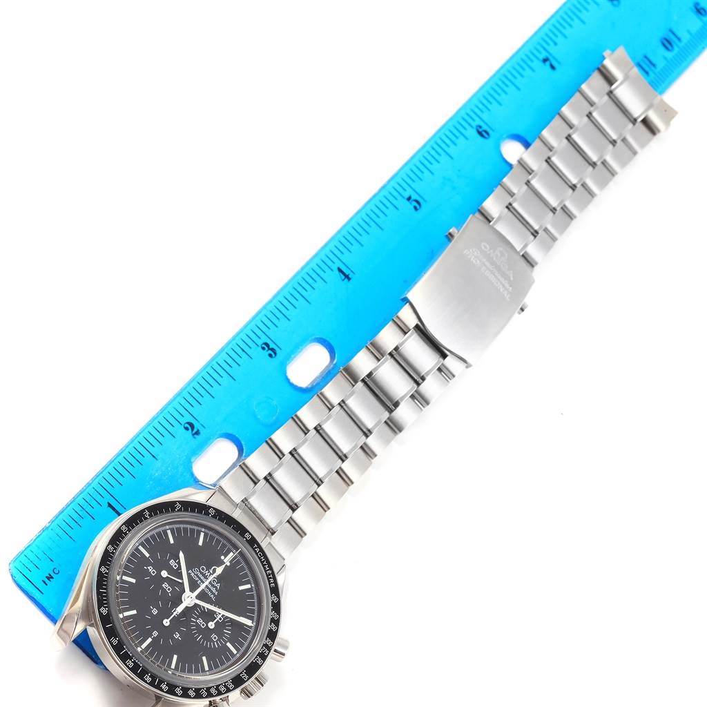 The image shows an Omega Speedmaster 3573.50.00 Men
s Stainless Steel Black Dial 3573.50.00 Men
s Stainless Steel Black Dial watch laid flat with its dial and metal bracelet visible alongside a blue ruler.