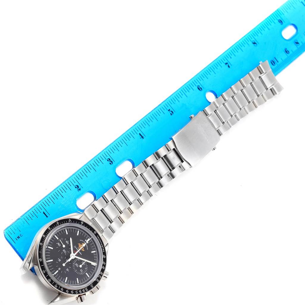 This image shows an Omega Speedmaster 311.30.42.30.01.001 Men
s Stainless Steel Black Dial 311.30.42.30.01.001 Men
s Stainless Steel Black Dial watch laying flat with a metal bracelet next to a blue ruler for measurement.