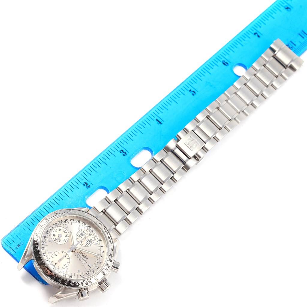 The image shows a top-down view of an Omega Speedmaster 3523.30.00 Men
s Stainless Steel Silver Dial 3523.30.00 Men
s Stainless Steel Silver Dial watch with its stainless steel bracelet beside a blue ruler.