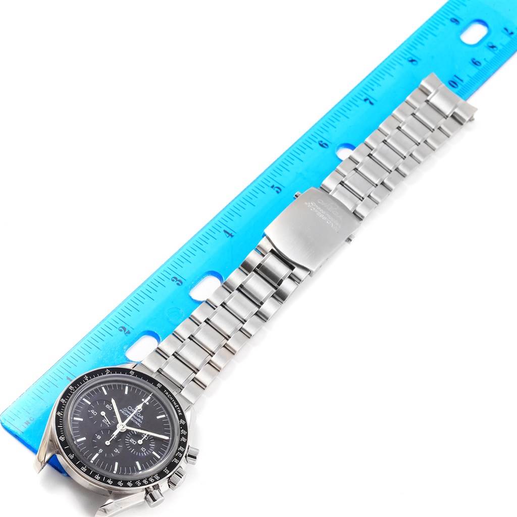 The image shows an Omega Speedmaster 3573.50.00 Men
s Stainless Steel Black Dial 3573.50.00 Men
s Stainless Steel Black Dial watch lying flat, with the face, bracelet, and clasp visible, next to a blue ruler for measurement.