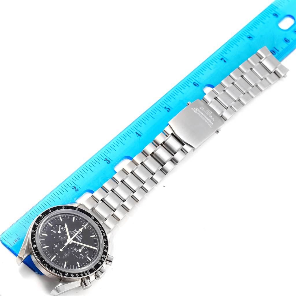 The Omega Speedmaster 3573.50.00 Men
s Stainless Steel Black Dial 3573.50.00 Men
s Stainless Steel Black Dial watch is shown from an aerial view, displaying the full dial and stainless steel bracelet next to a blue ruler.