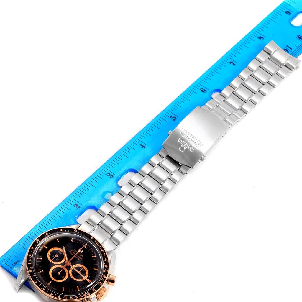 The Omega Speedmaster 3566.51.00 Men's Steel and Gold (two tone) Black Dial 3566.51.00 Men's Steel and Gold (two tone) Black Dial watch is shown flat from an overhead angle, displaying its face, band, and clasp next to a ruler for size reference.