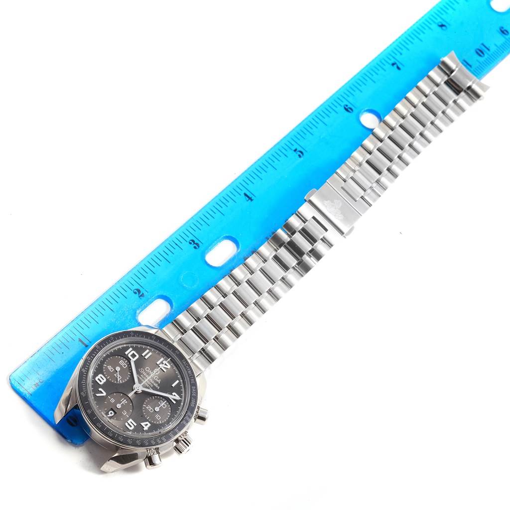 The image shows an Omega Speedmaster 324.30.38.40.06.001 Men
s Stainless Steel Grey Dial 324.30.38.40.06.001 Men
s Stainless Steel Grey Dial watch with a stainless steel band next to a blue ruler for size reference.