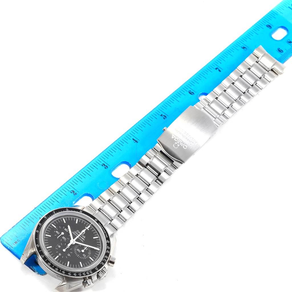 This image shows an Omega Speedmaster 3573.50.00 Men
s Stainless Steel Black Dial 3573.50.00 Men
s Stainless Steel Black Dial watch laid flat next to a ruler, displaying the face and stainless steel bracelet.