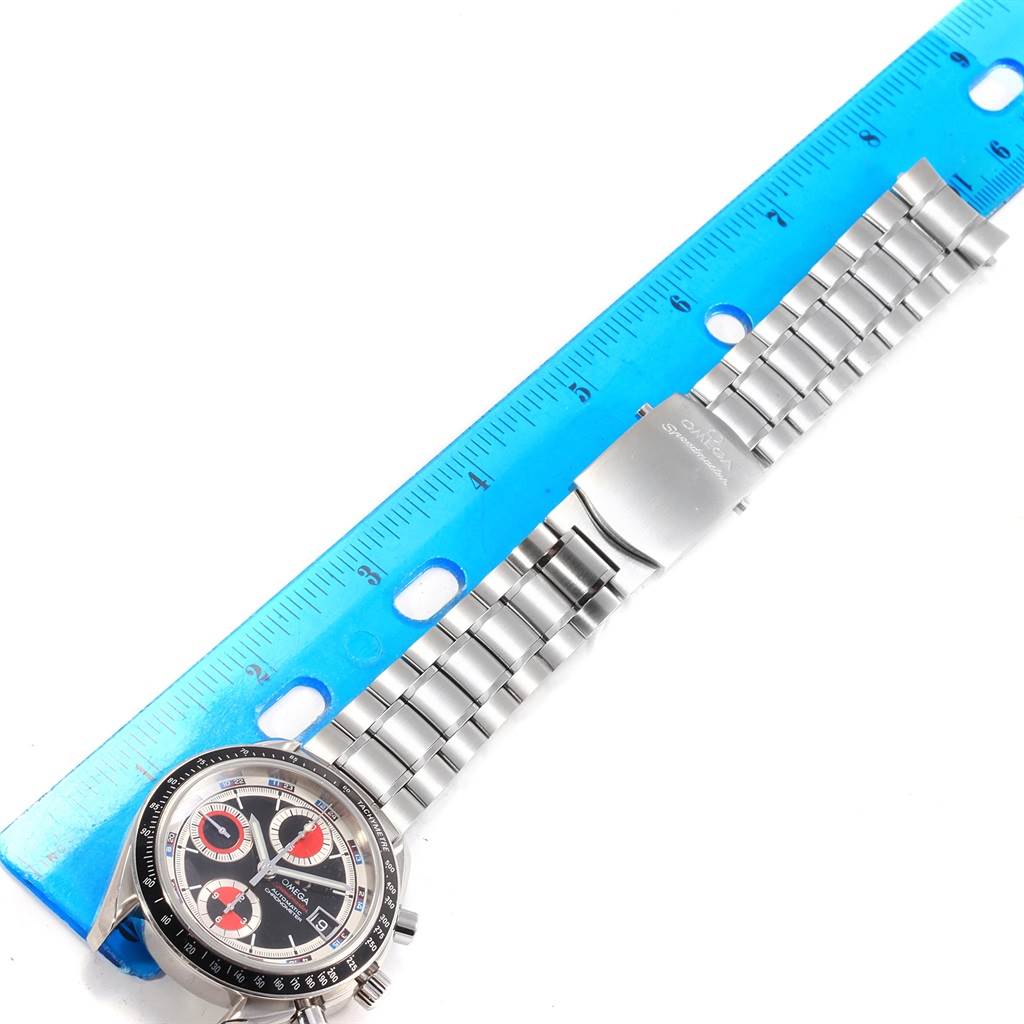 The image shows the face and stainless steel bracelet of an Omega Speedmaster 3210.52.00 Men
s Stainless Steel Black Dial 3210.52.00 Men
s Stainless Steel Black Dial watch, positioned next to a blue ruler for scale.