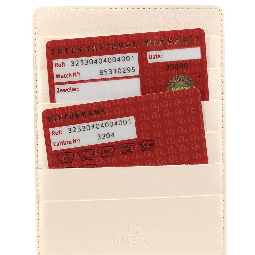 The image shows warranty cards and pictogram cards for the Omega Speedmaster 323.30.40.40.04.001 Men's Stainless Steel White Dial 323.30.40.40.04.001 Men's Stainless Steel White Dial watch tucked into a beige cardholder.
