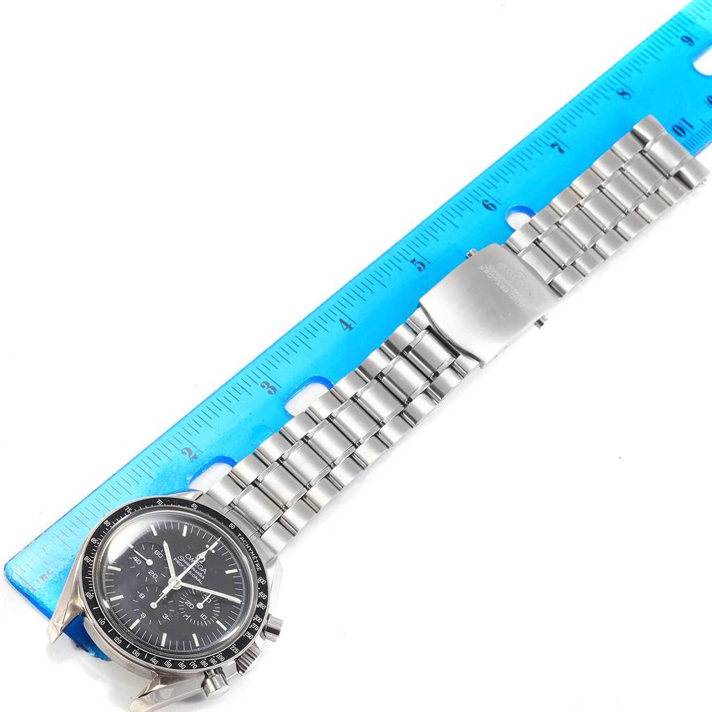 The image shows an Omega Speedmaster 3572.50.00 Men
s Stainless Steel Black Dial 3572.50.00 Men
s Stainless Steel Black Dial watch from a top-down angle next to a blue ruler, displaying the dial and metal bracelet.