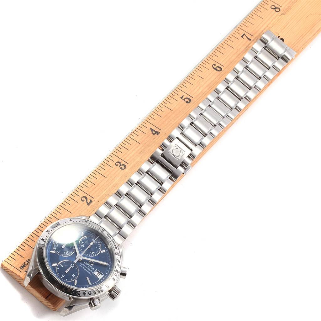 The image shows the Omega Speedmaster 3513.80.00 Men
s Stainless Steel Blue Dial 3513.80.00 Men
s Stainless Steel Blue Dial watch from a top-down angle, focusing on the face and metal bracelet laid against a ruler.