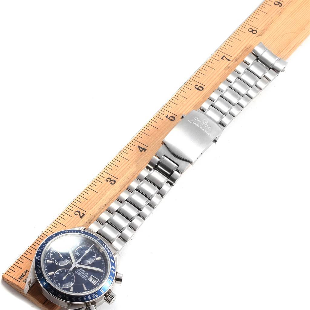 The Omega Speedmaster 3212.80.00 Men
s Stainless Steel Blue Dial 3212.80.00 Men
s Stainless Steel Blue Dial watch is shown from a top-down angle, displaying the watch face, metal bracelet, and clasp along a ruler.