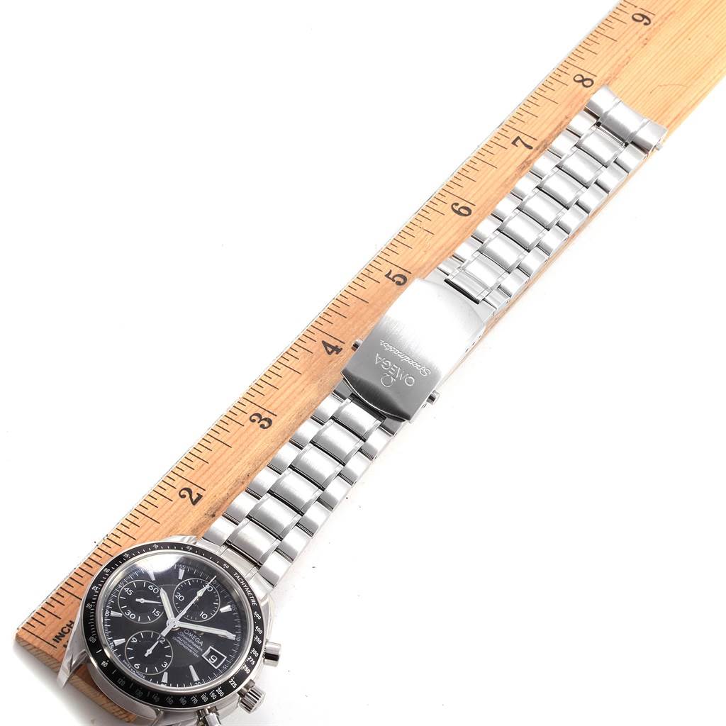 The image shows an Omega Speedmaster 3210.50.00 Men
s Stainless Steel Black Dial 3210.50.00 Men
s Stainless Steel Black Dial watch laid flat with the face, bracelet, and clasp visible, alongside a wooden ruler for scale.