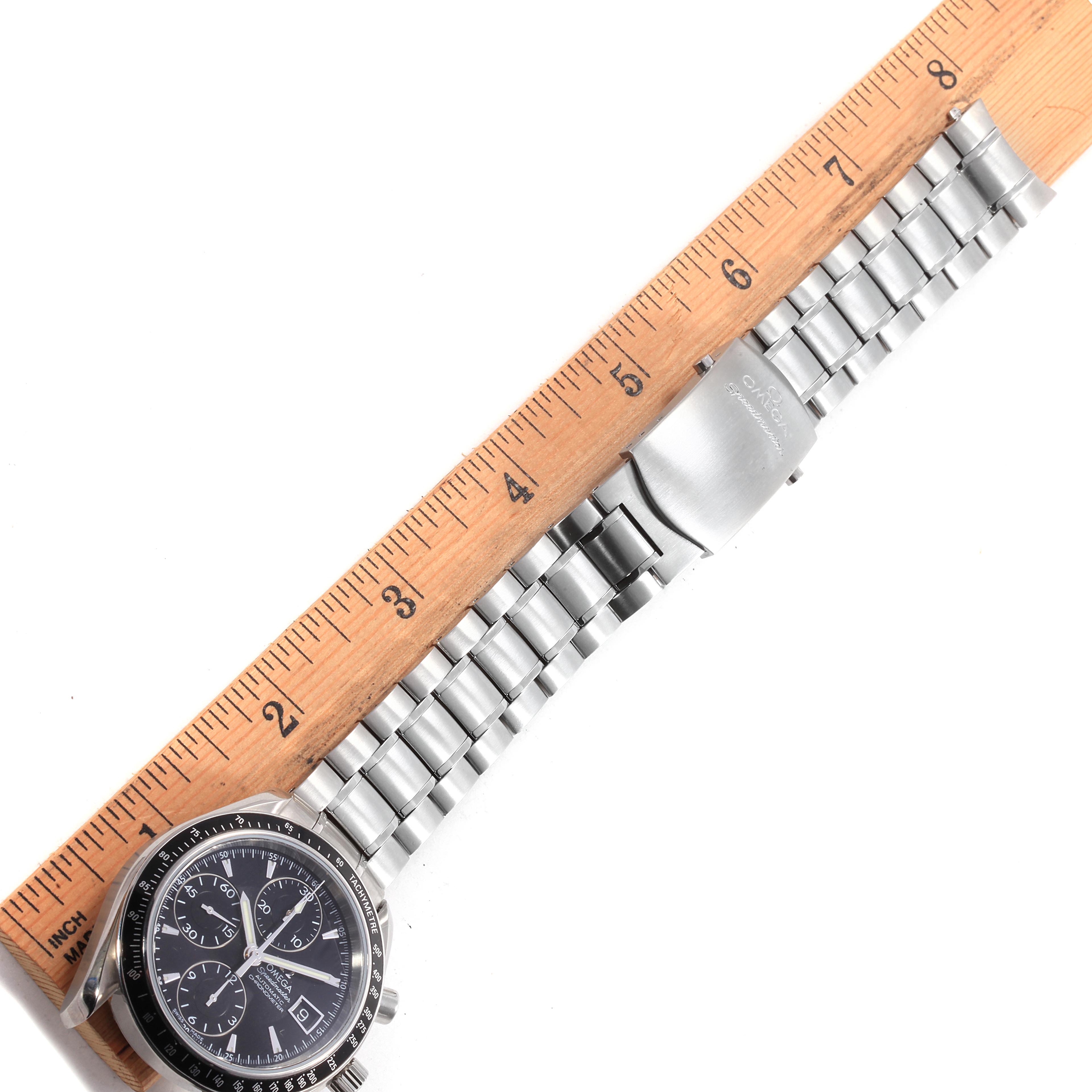 This image shows the Omega Speedmaster 3210.50.00 Men
s Stainless Steel Black Dial 3210.50.00 Men
s Stainless Steel Black Dial watch laid flat next to a ruler, displaying its face and metal band.