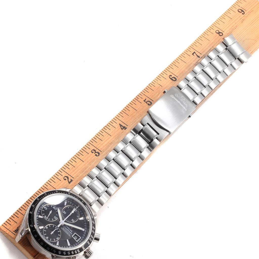 The Omega Speedmaster 3210.50.00 Men
s Stainless Steel Black Dial 3210.50.00 Men
s Stainless Steel Black Dial watch is shown from a top-down angle, displaying its face, bracelet, and clasp next to a ruler.