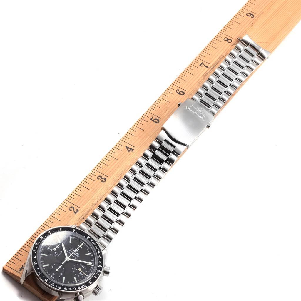The image shows an Omega Speedmaster 3539.50.00 Men
s Stainless Steel Black Dial 3539.50.00 Men
s Stainless Steel Black Dial watch laid flat next to a wooden ruler, displaying its face, bezel, and stainless steel bracelet.