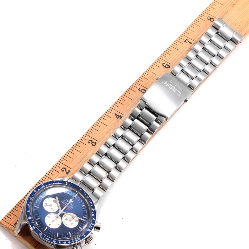 The image shows the Omega Speedmaster 3565.80.00 Men
s Stainless Steel Blue Dial 3565.80.00 Men
s Stainless Steel Blue Dial watch lying flat with its band extended next to a wooden ruler for size reference.