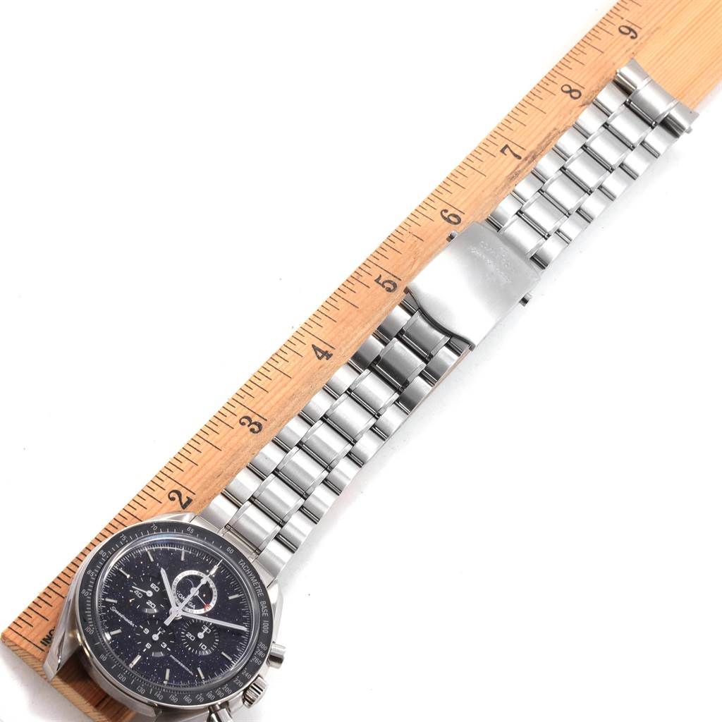 The Omega Speedmaster 311.30.44.32.01.001 Men
s Stainless Steel Black Dial 311.30.44.32.01.001 Men
s Stainless Steel Black Dial watch is shown from a top-down angle, featuring the dial, bezel, and entire metal bracelet against a ruler for scale.