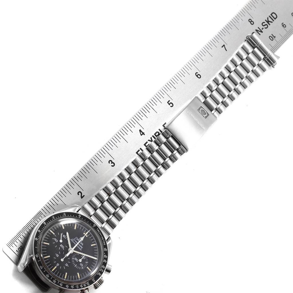 The image shows an Omega Speedmaster 145.022 Men
s Stainless Steel Black Dial 145.022 Men
s Stainless Steel Black Dial watch laid flat, with its dial and metal bracelet aligned next to a ruler for measurement.