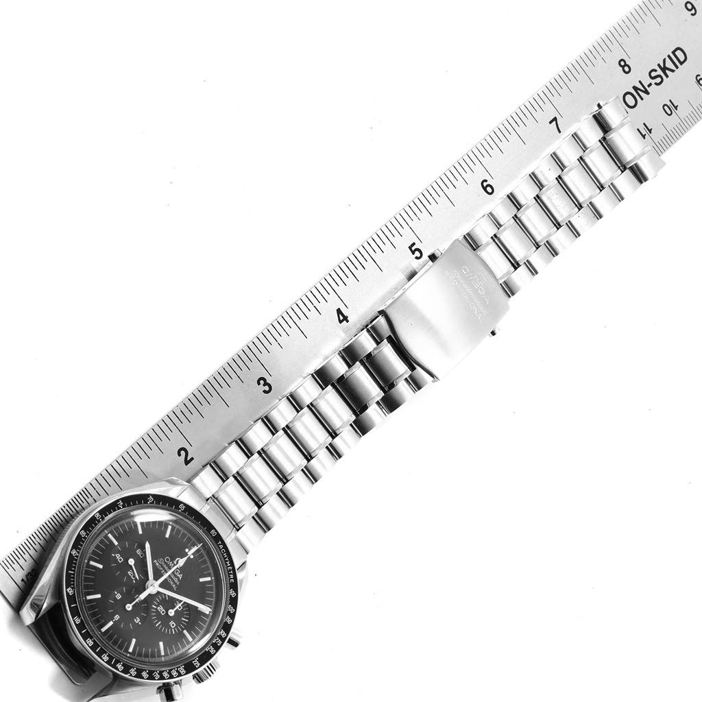 The image shows an Omega Speedmaster 3570.50.00 Men
s Stainless Steel Black Dial 3570.50.00 Men
s Stainless Steel Black Dial watch with a metal bracelet next to a ruler, viewed from a top-down angle.