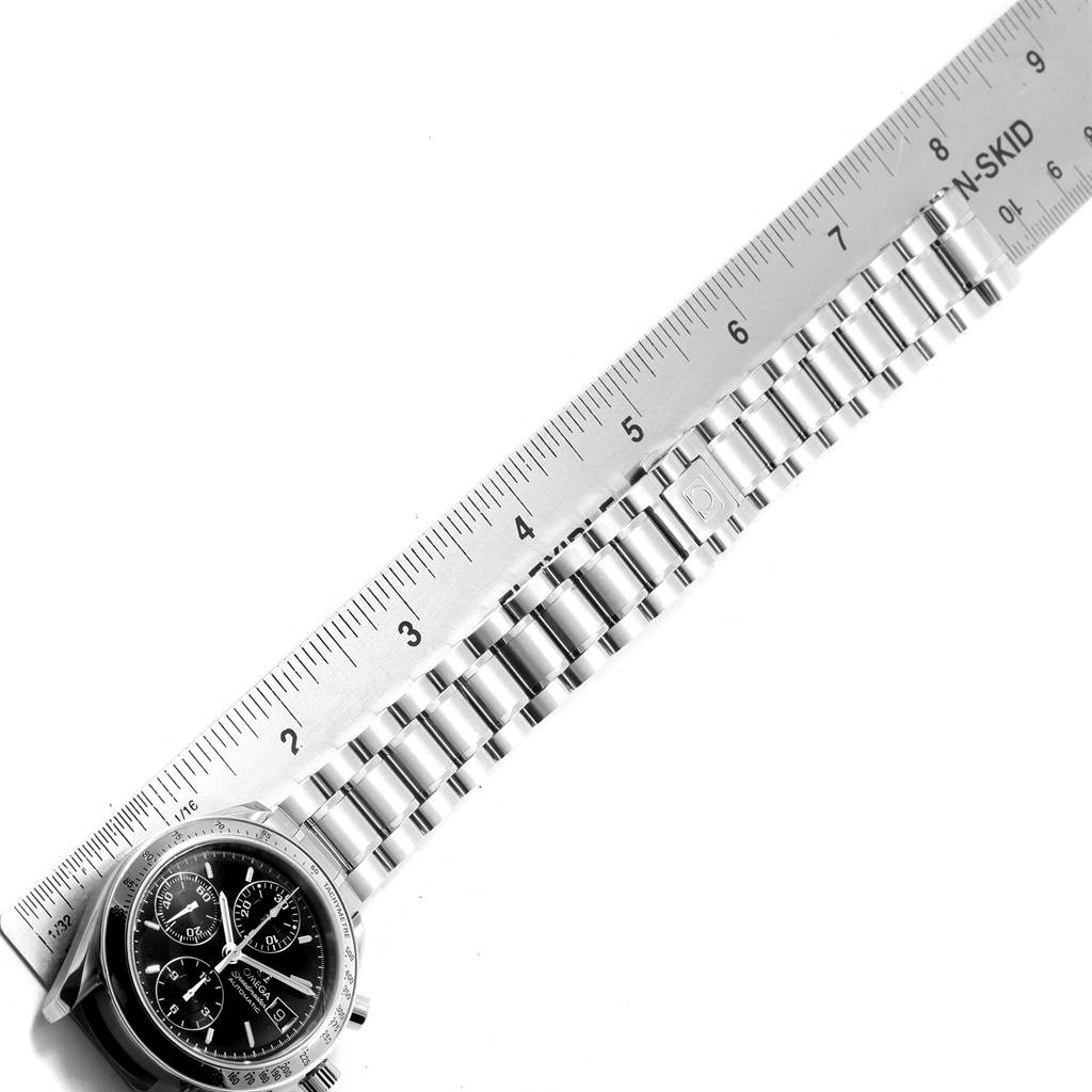 The image shows an Omega Speedmaster 3513.50.00 Men
s Stainless Steel Black Dial 3513.50.00 Men
s Stainless Steel Black Dial watch face and part of its metal bracelet laid next to a ruler.