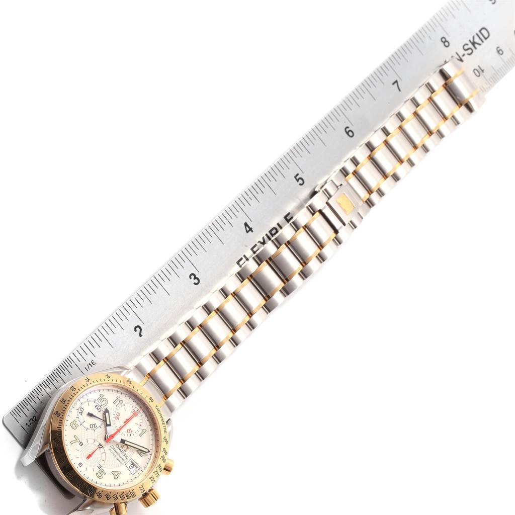 The Omega Speedmaster 3313.33.00 Men's Steel and Gold (two tone) White Dial 3313.33.00 Men's Steel and Gold (two tone) White Dial watch is shown from a top view, displaying the face, bezel, and part of the metal bracelet alongside a ruler.