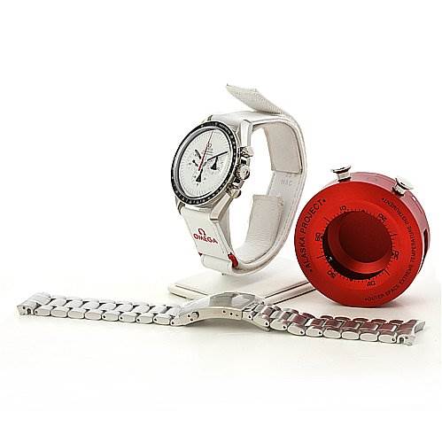 The image shows an Omega Speedmaster 31132423004001 OR 311.   32.   42.   30.   04.   001 Men's Stainless Steel White Dial 31132423004001 OR 311.   32.   42.   30.   04.   001 Men's Stainless Steel White Dial watch from a front-left angle, with additional watch bands and a red accessory.