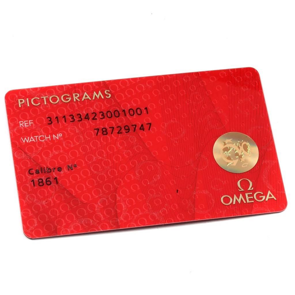 The image shows a red Omega Speedmaster 311.33.42.30.01.001 Men
s Stainless Steel Black Dial 311.33.42.30.01.001 Men
s Stainless Steel Black Dial warranty or pictograms card at an angle, displaying reference and watch numbers.