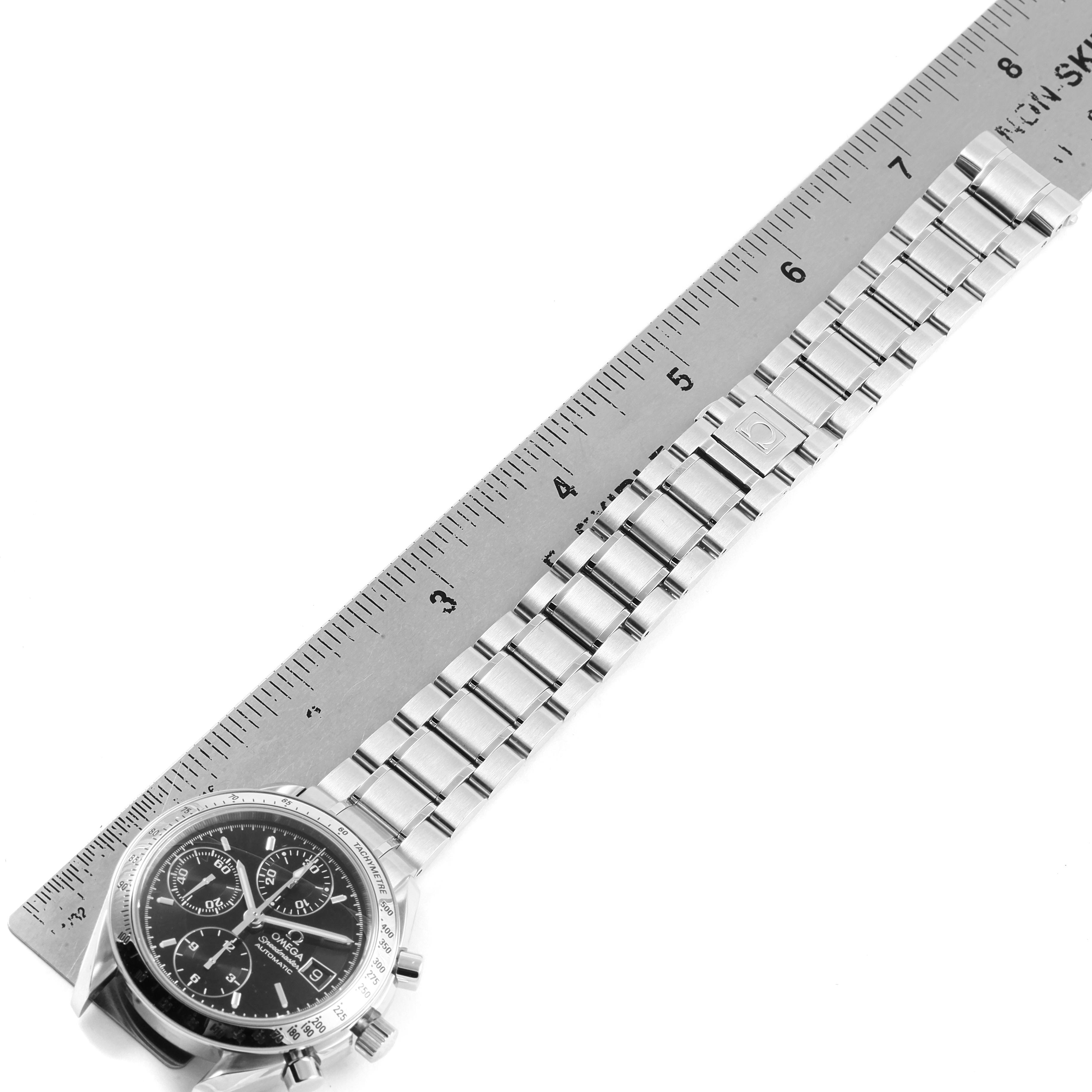 The image shows an Omega Speedmaster 3513.50.00 Men
s Stainless Steel Black Dial 3513.50.00 Men
s Stainless Steel Black Dial watch placed diagonally next to a ruler, highlighting the watch
s face and metal bracelet.
