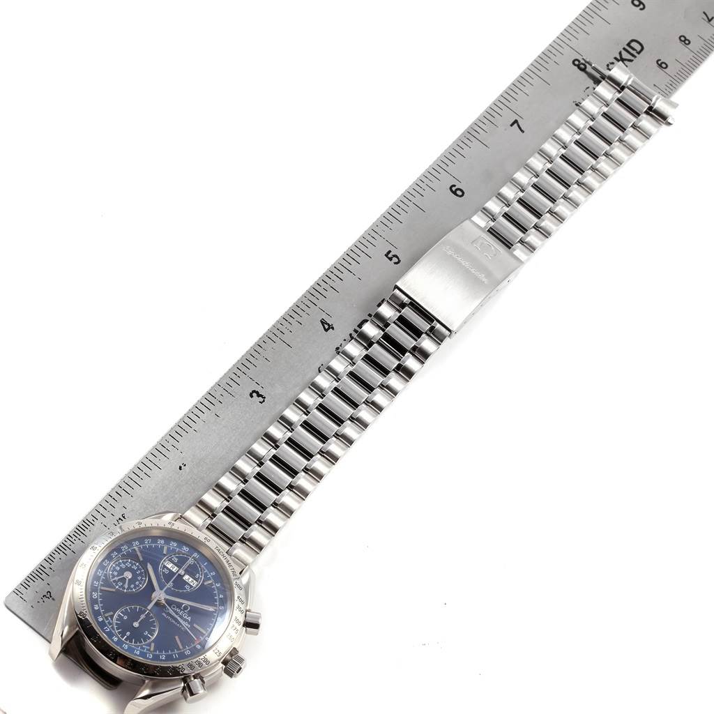The image shows an Omega Speedmaster 3521.80.00 Men
s Stainless Steel Blue Dial 3521.80.00 Men
s Stainless Steel Blue Dial watch placed with a steel ruler next to its metal bracelet and clasp.