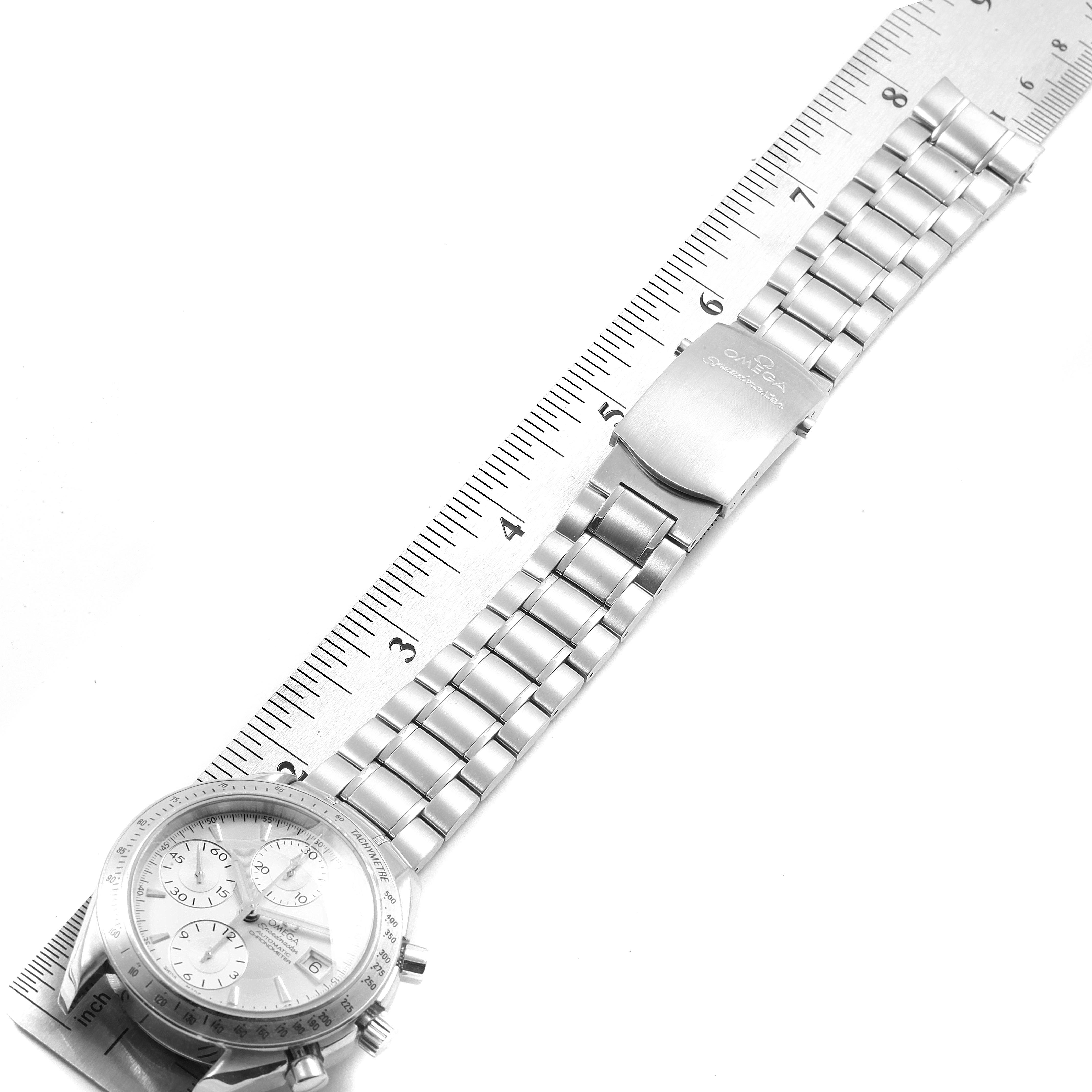 The image shows a top-down view of an Omega Speedmaster 3211.30.00 Men's Stainless Steel Silver Dial 3211.30.00 Men's Stainless Steel Silver Dial watch, highlighting the face, bezel, and metal bracelet against a ruler.