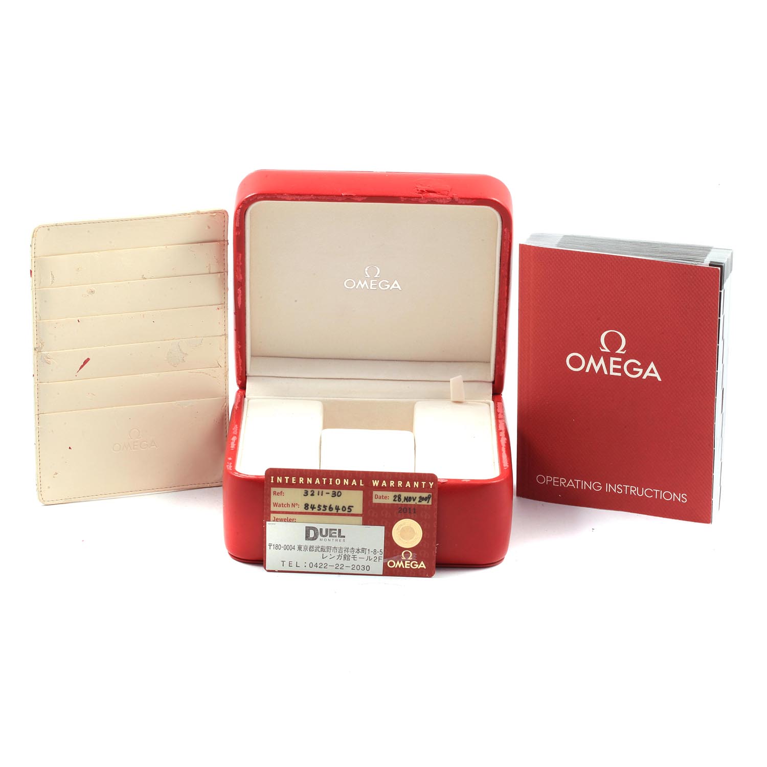 The image shows an Omega Speedmaster 3211.30.00 Men's Stainless Steel Silver Dial 3211.30.00 Men's Stainless Steel Silver Dial box, warranty card, cardholder, and operating instructions from a front angle.